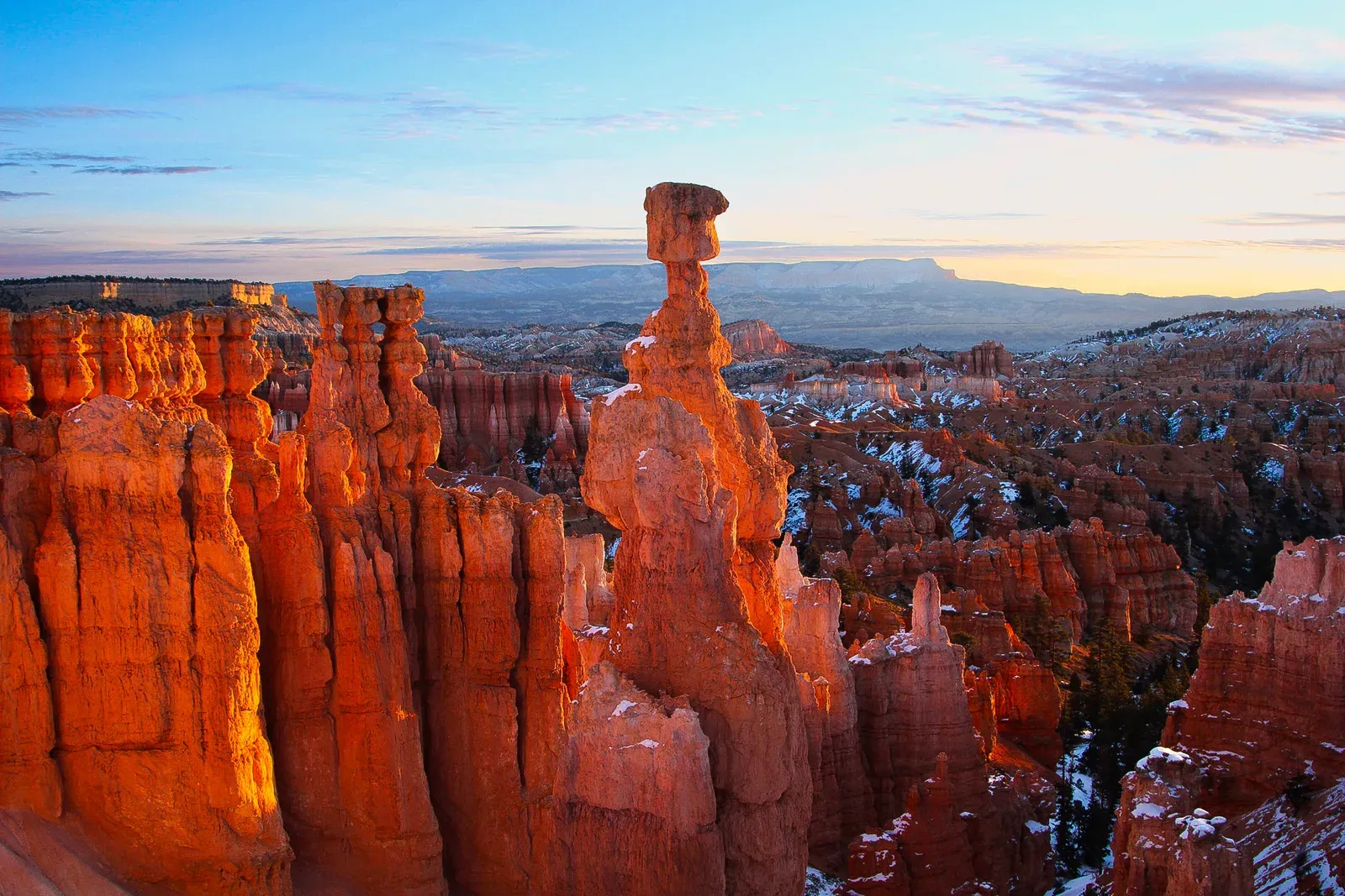 Glowing orange hoodoos and a balanced rock tower at sunrise.
