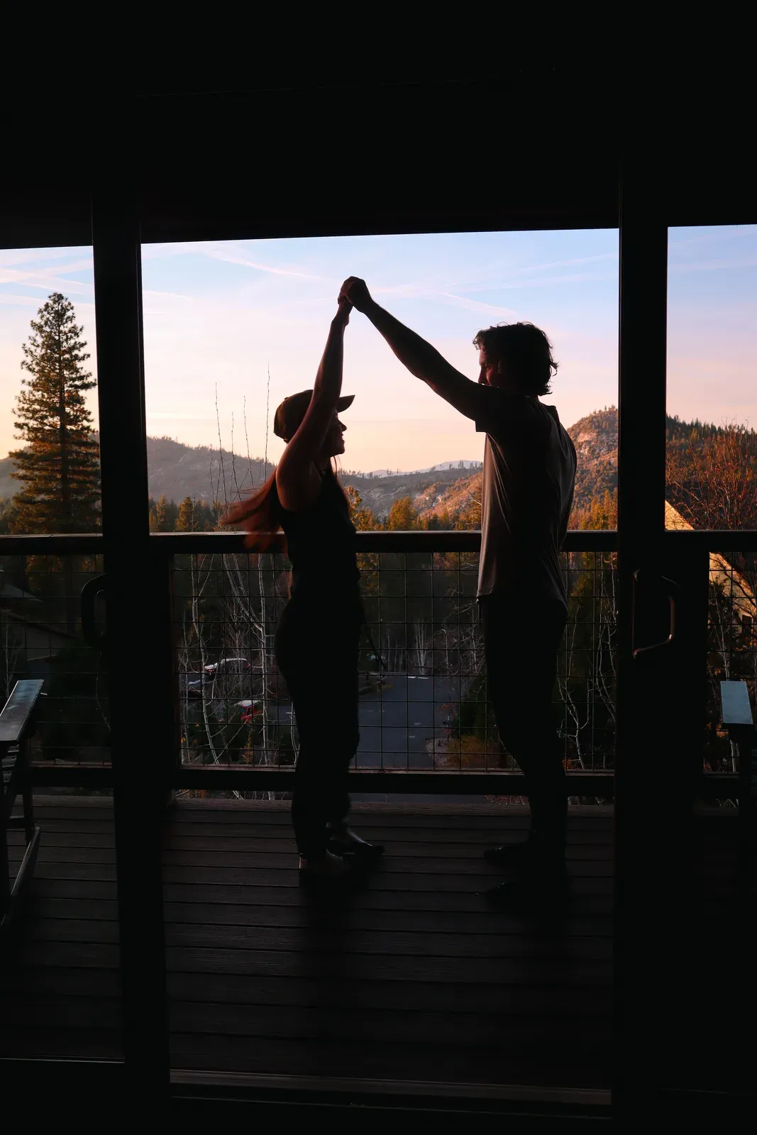 Brendon and Kaylee dancing in silhouette in a cabin window at sunset.