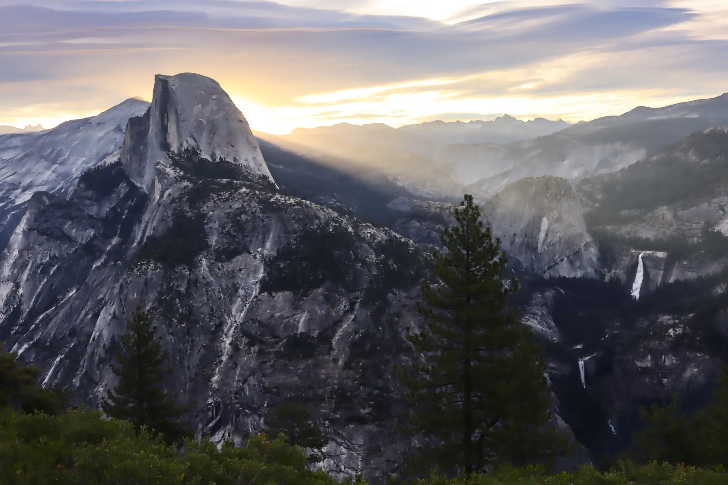 Half Dome with light rays across the valley at sunrise.