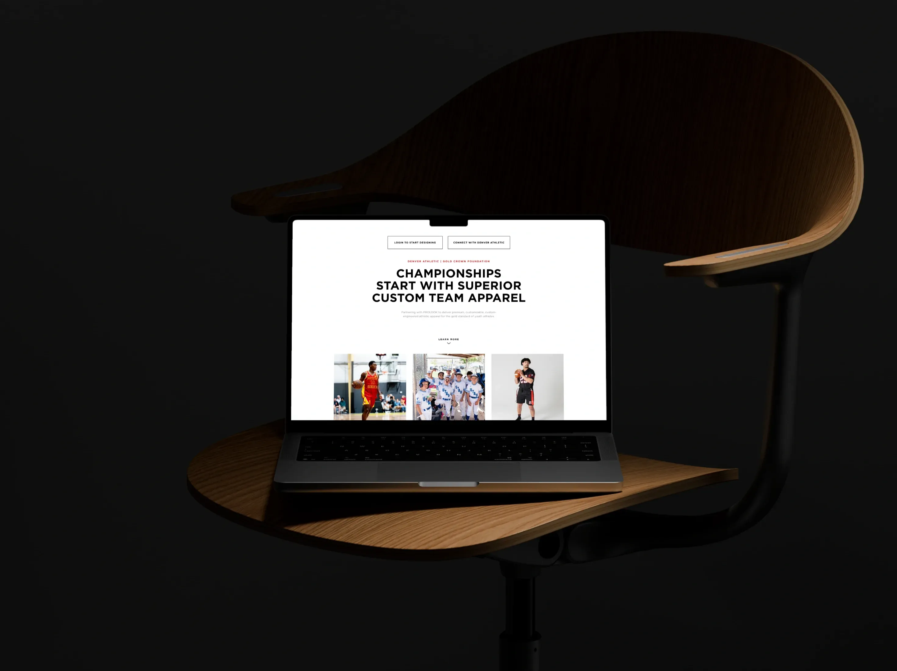 A MacBook on the seat of a curved wooden chair in a dark room, showing the Denver Athletic and Gold Crown Foundation page — Login to start designing and Connect with Denver Athletic buttons, the headline Championships start with superior custom team apparel, Learn more, and the tops of three tile photos for basketball, baseball and flag football.