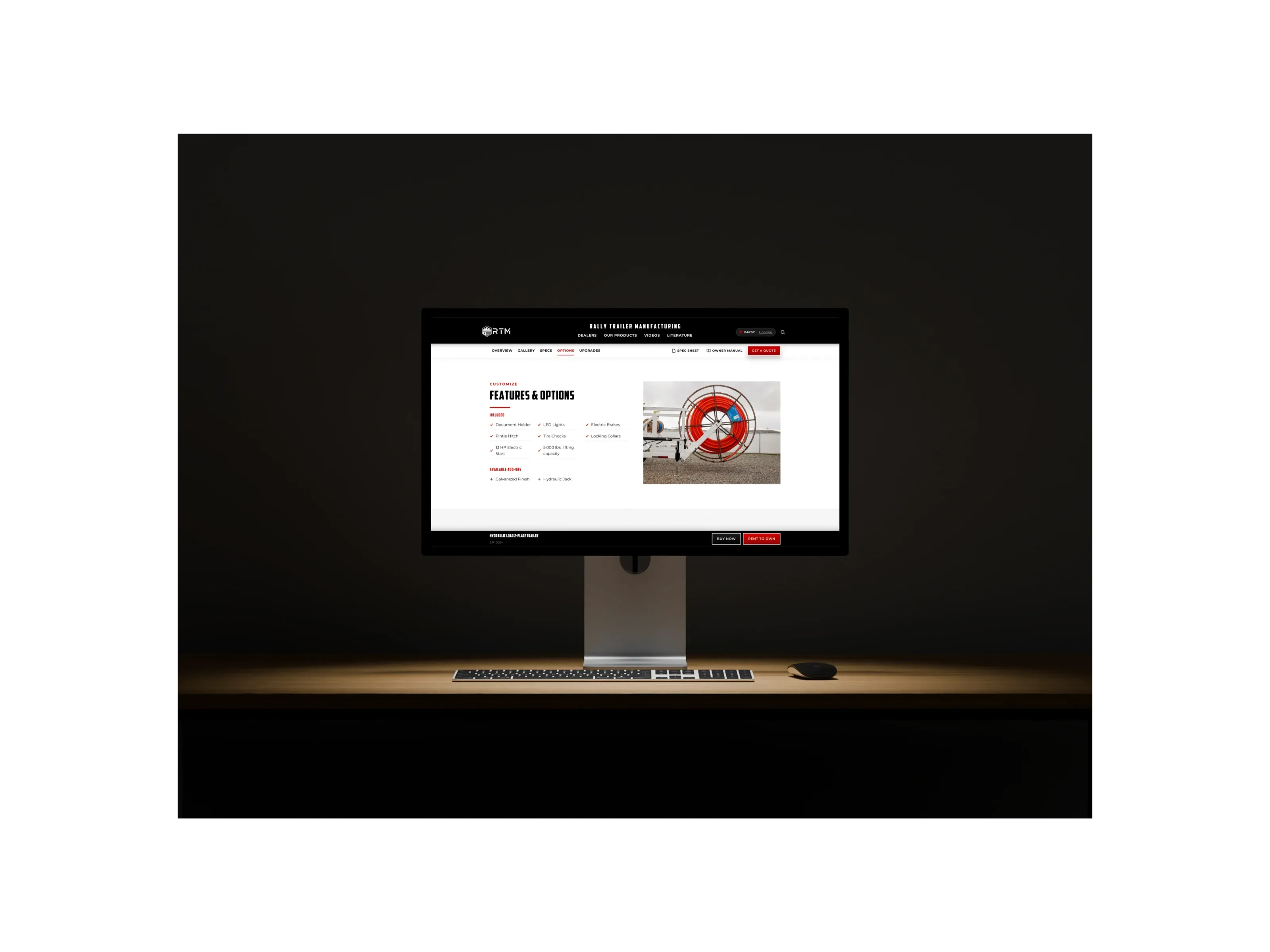 An Apple Studio Display on a desk in a dark room, showing the Features and Options section of a trailer page on the new site.